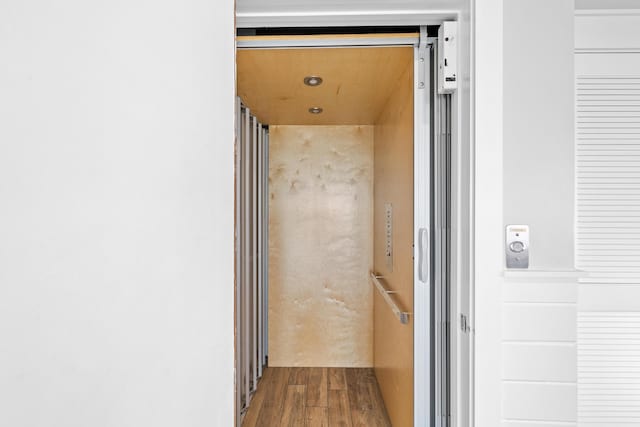 hallway featuring elevator and wood finished floors