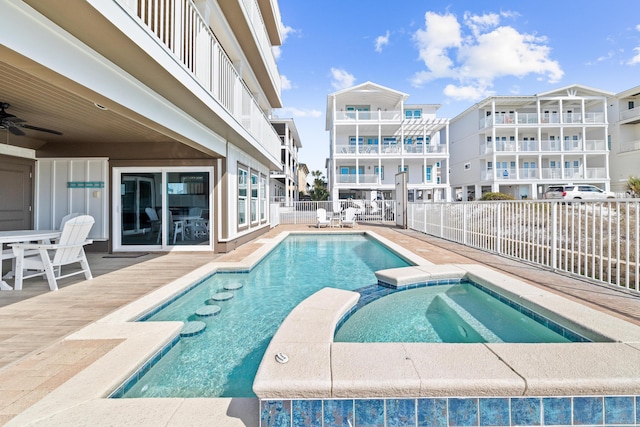 view of pool featuring a pool with connected hot tub, fence, and ceiling fan