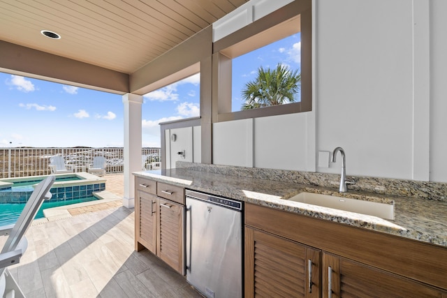 view of patio featuring a pool with connected hot tub, a sink, and an outdoor kitchen