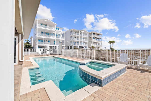 view of swimming pool featuring a pool with connected hot tub and fence