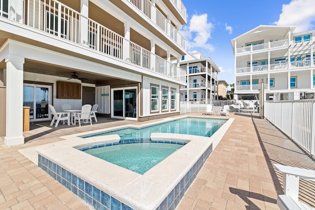 view of swimming pool featuring a pool with connected hot tub, ceiling fan, a patio, and fence