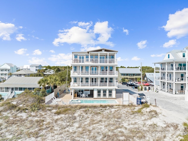 back of house featuring a balcony, fence, an outdoor pool, and a patio