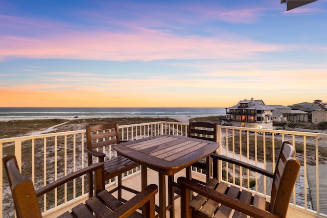 deck at dusk with a water view and a beach view