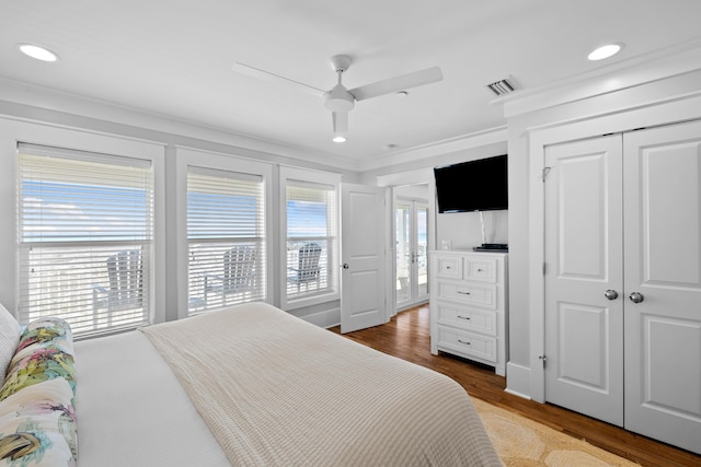 bedroom featuring multiple windows, ornamental molding, and wood finished floors