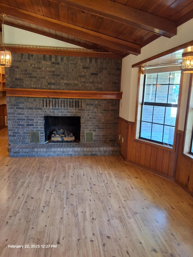 unfurnished living room featuring vaulted ceiling with beams, a brick fireplace, wainscoting, wood finished floors, and wooden ceiling