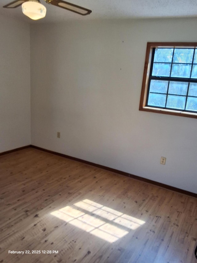 empty room featuring a ceiling fan, light wood-style flooring, and baseboards