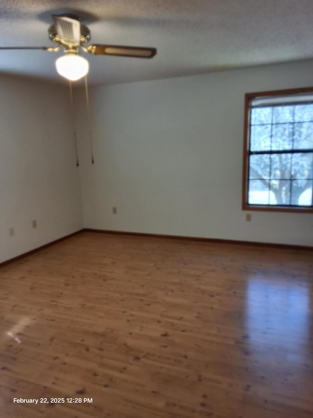 spare room with a ceiling fan, baseboards, and dark wood-style flooring