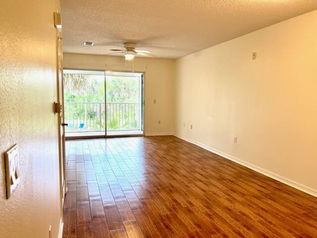 spare room featuring dark wood-style flooring, ceiling fan, a textured ceiling, and baseboards