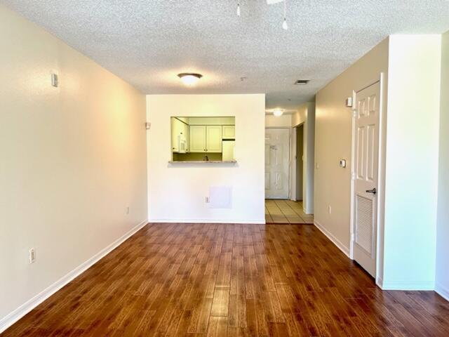 empty room featuring dark wood finished floors, a textured ceiling, and baseboards