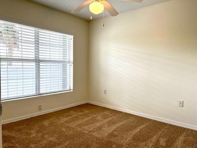 carpeted empty room with a ceiling fan and baseboards