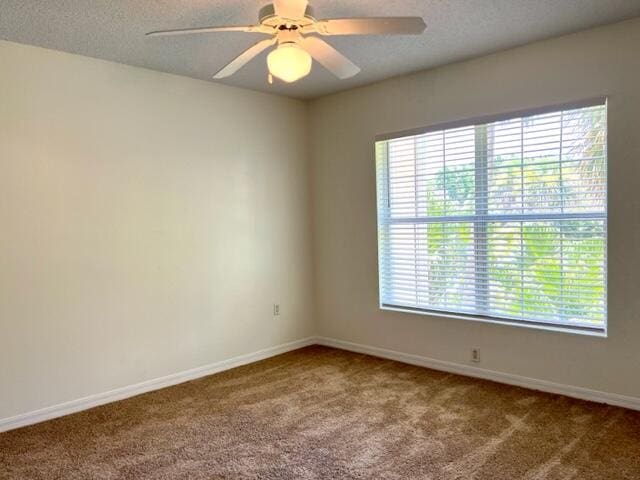 unfurnished room with carpet flooring, ceiling fan, a textured ceiling, and baseboards