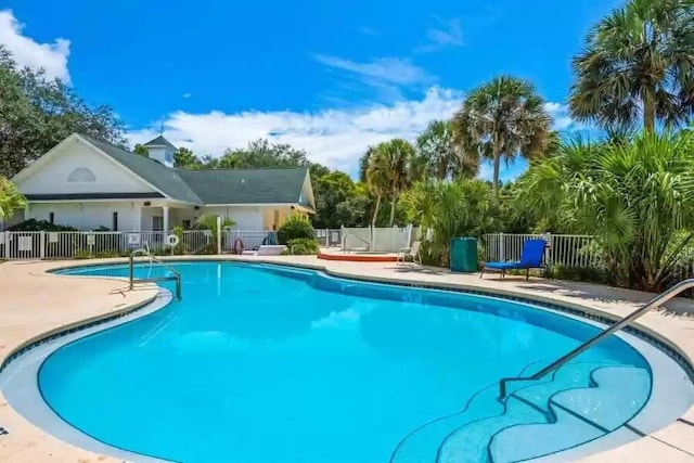 community pool with a patio area and fence