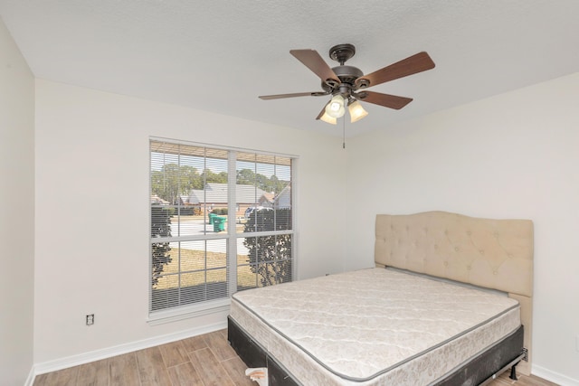 bedroom with ceiling fan, wood finished floors, and baseboards