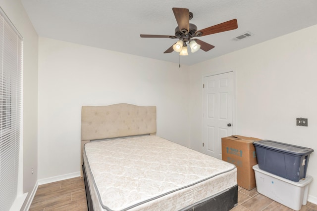 bedroom featuring a ceiling fan, light wood-type flooring, visible vents, and baseboards