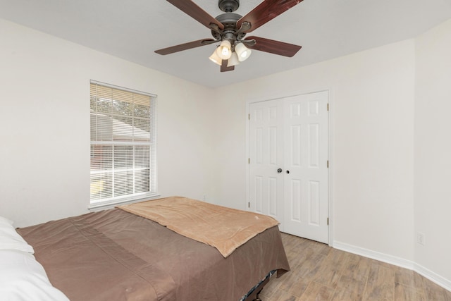 bedroom with a ceiling fan, a closet, baseboards, and light wood finished floors