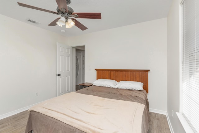 bedroom with ceiling fan, light wood-style flooring, visible vents, and baseboards