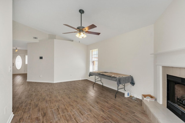 living area featuring a tile fireplace, visible vents, lofted ceiling, and wood finished floors