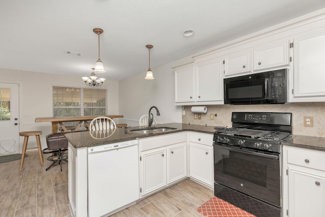 kitchen with a peninsula, a sink, white cabinets, hanging light fixtures, and black appliances