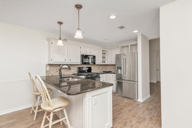 kitchen with black appliances, a peninsula, a sink, and white cabinets