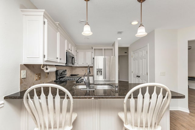 kitchen featuring visible vents, dark stone countertops, stainless steel appliances, white cabinetry, and pendant lighting