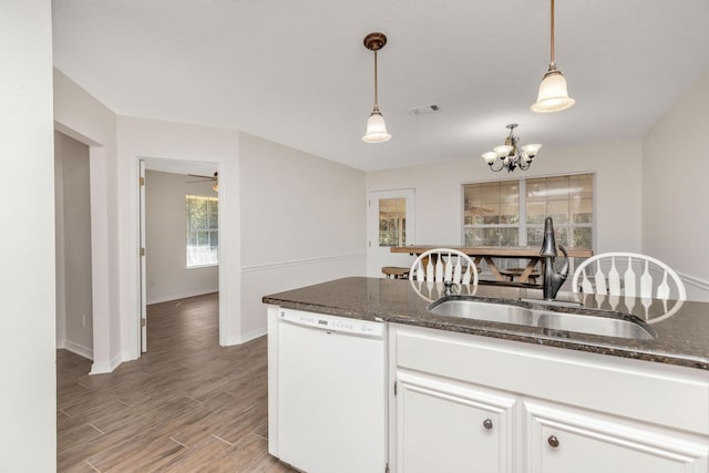 kitchen featuring visible vents, white cabinets, dishwasher, hanging light fixtures, and a sink