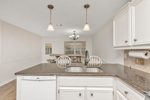 kitchen featuring white dishwasher, a sink, white cabinetry, and decorative light fixtures