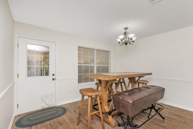 dining area featuring dark wood finished floors, baseboards, and an inviting chandelier