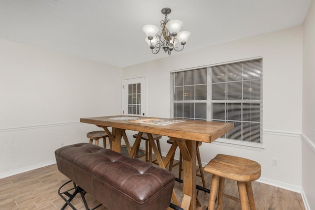 dining area featuring baseboards, a notable chandelier, and light wood finished floors