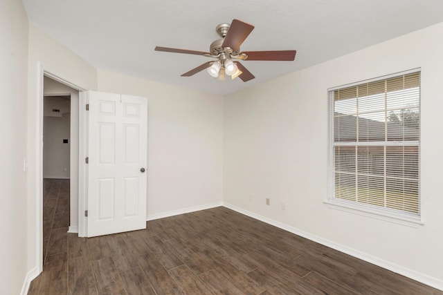 unfurnished room with a ceiling fan, baseboards, and dark wood-style flooring