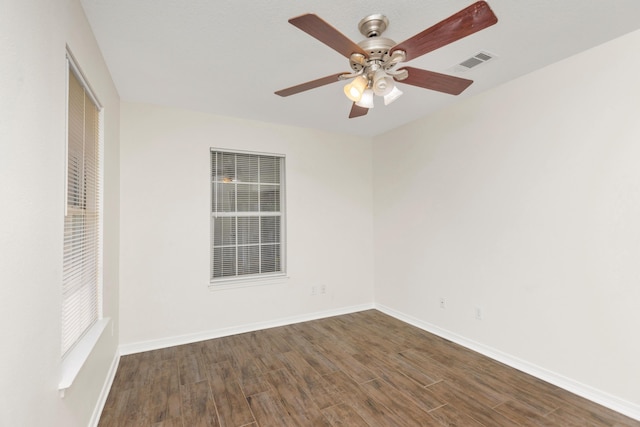 empty room featuring dark wood-style floors, ceiling fan, visible vents, and baseboards