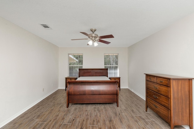 bedroom with visible vents, baseboards, a ceiling fan, and wood finish floors