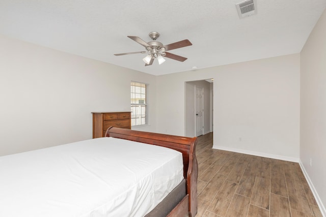 bedroom featuring visible vents, ceiling fan, baseboards, and wood finished floors