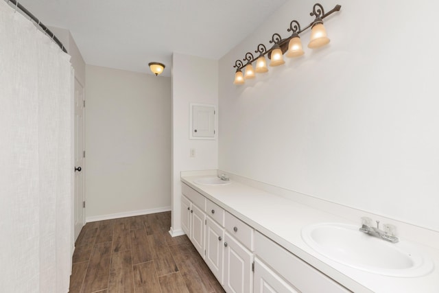 bathroom with double vanity, a sink, baseboards, and wood finished floors