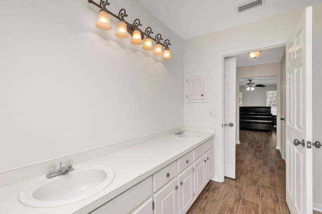 bathroom featuring wood finish floors, visible vents, a sink, and double vanity