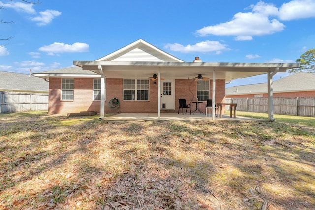 back of property featuring ceiling fan, a fenced backyard, brick siding, a lawn, and a patio area