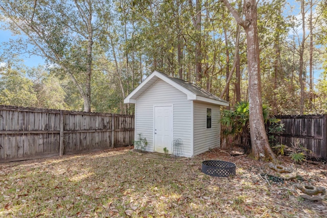 view of shed with a fenced backyard and a fire pit