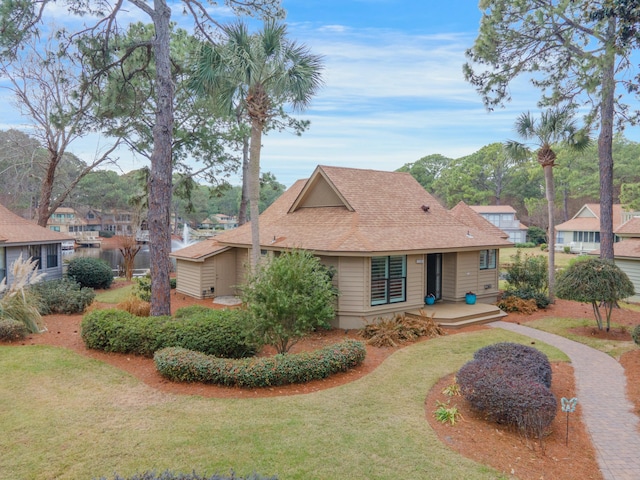 view of front facade with roof with shingles and a front yard