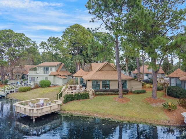 back of property with a water view, a balcony, and a lawn