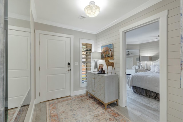 entryway with visible vents, light wood-style flooring, and crown molding