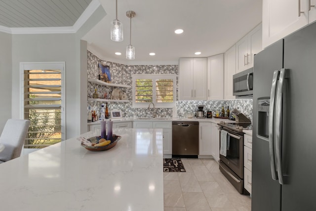 kitchen with hanging light fixtures, appliances with stainless steel finishes, light stone countertops, and white cabinets