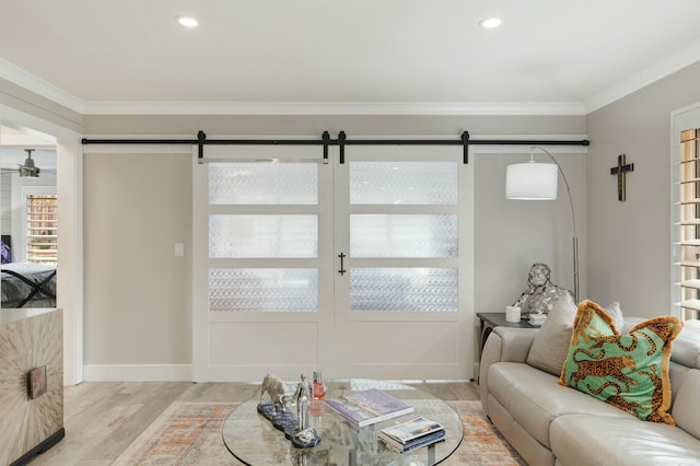 living area with light wood finished floors, a barn door, crown molding, and recessed lighting