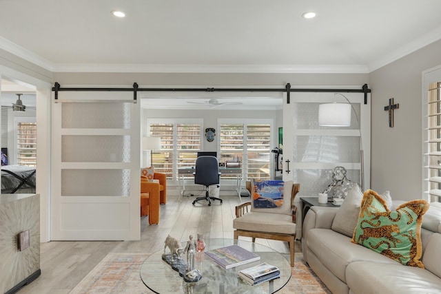 living room featuring ornamental molding, light wood finished floors, and a barn door