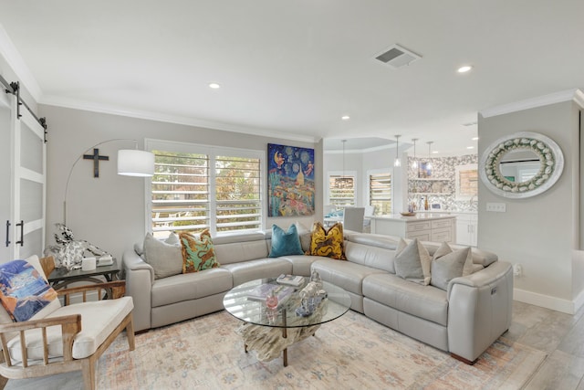 living room featuring visible vents, crown molding, baseboards, and a barn door