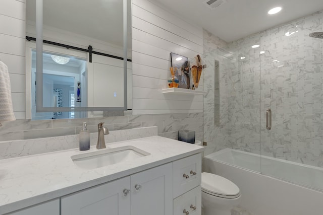 bathroom featuring tile walls, visible vents, toilet, enclosed tub / shower combo, and vanity