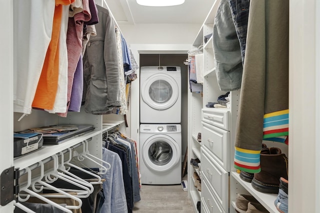 clothes washing area featuring stacked washer and dryer, laundry area, and light wood finished floors