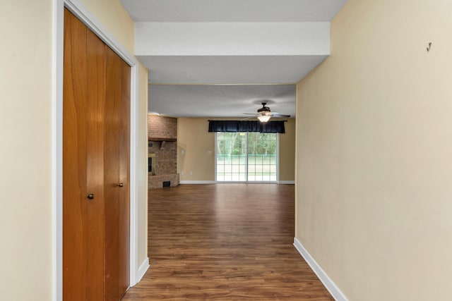 hallway with a textured ceiling, baseboards, and wood finished floors