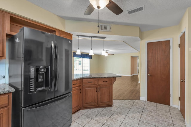 kitchen with ceiling fan, visible vents, brown cabinetry, and black fridge