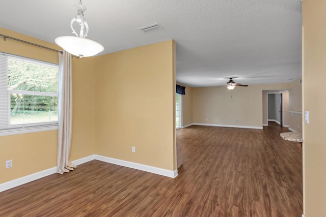 unfurnished room with baseboards, dark wood finished floors, and a textured ceiling