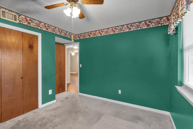 unfurnished bedroom featuring carpet, visible vents, a textured ceiling, and baseboards