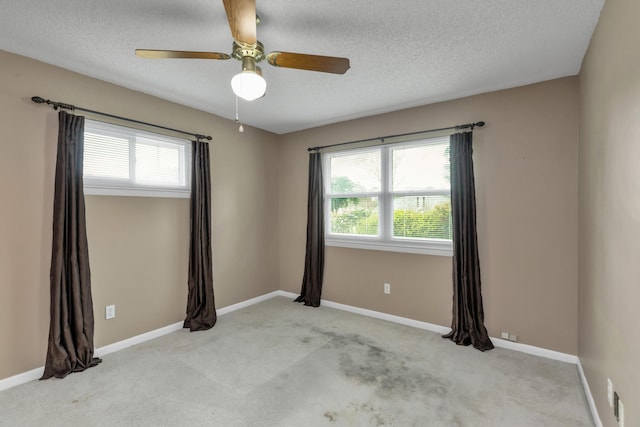 spare room with a textured ceiling, carpet floors, and baseboards